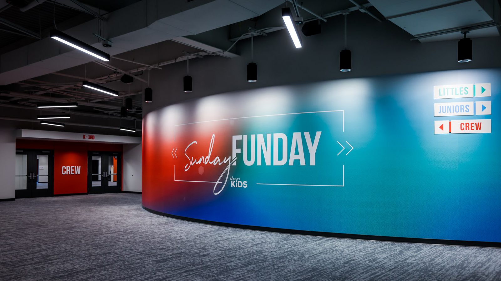 Red and blue wall in hallway that says "Sunday Funday Lifepoint Kids"