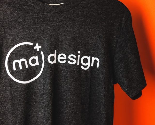 Gray t-shirt with MA Design logo in white; orange background