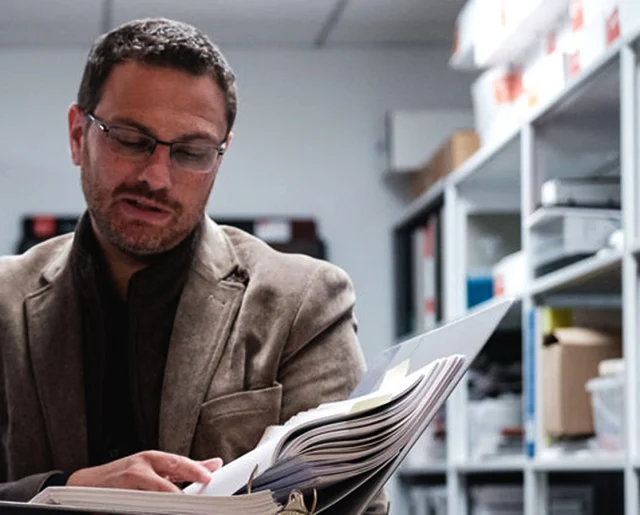 Kurt Beres looking at a code book open in his hands.